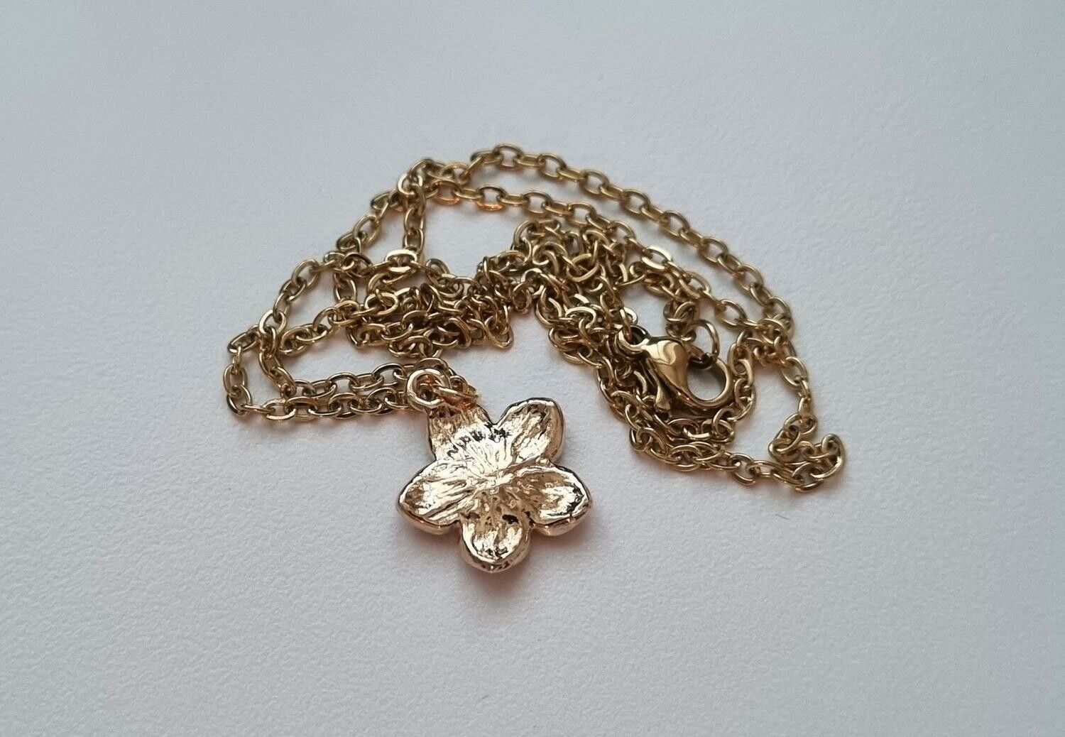 Guldfärgat halsband med en rosa blomma, blomberlock / charm