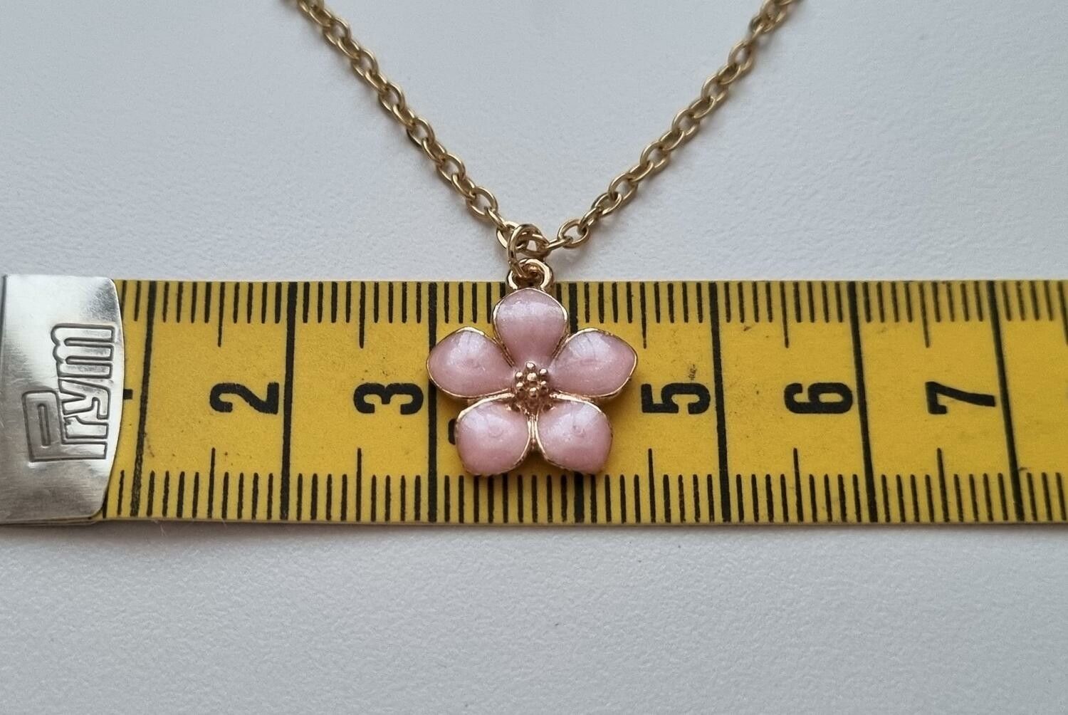 Guldfärgat halsband med en rosa blomma, blomberlock / charm