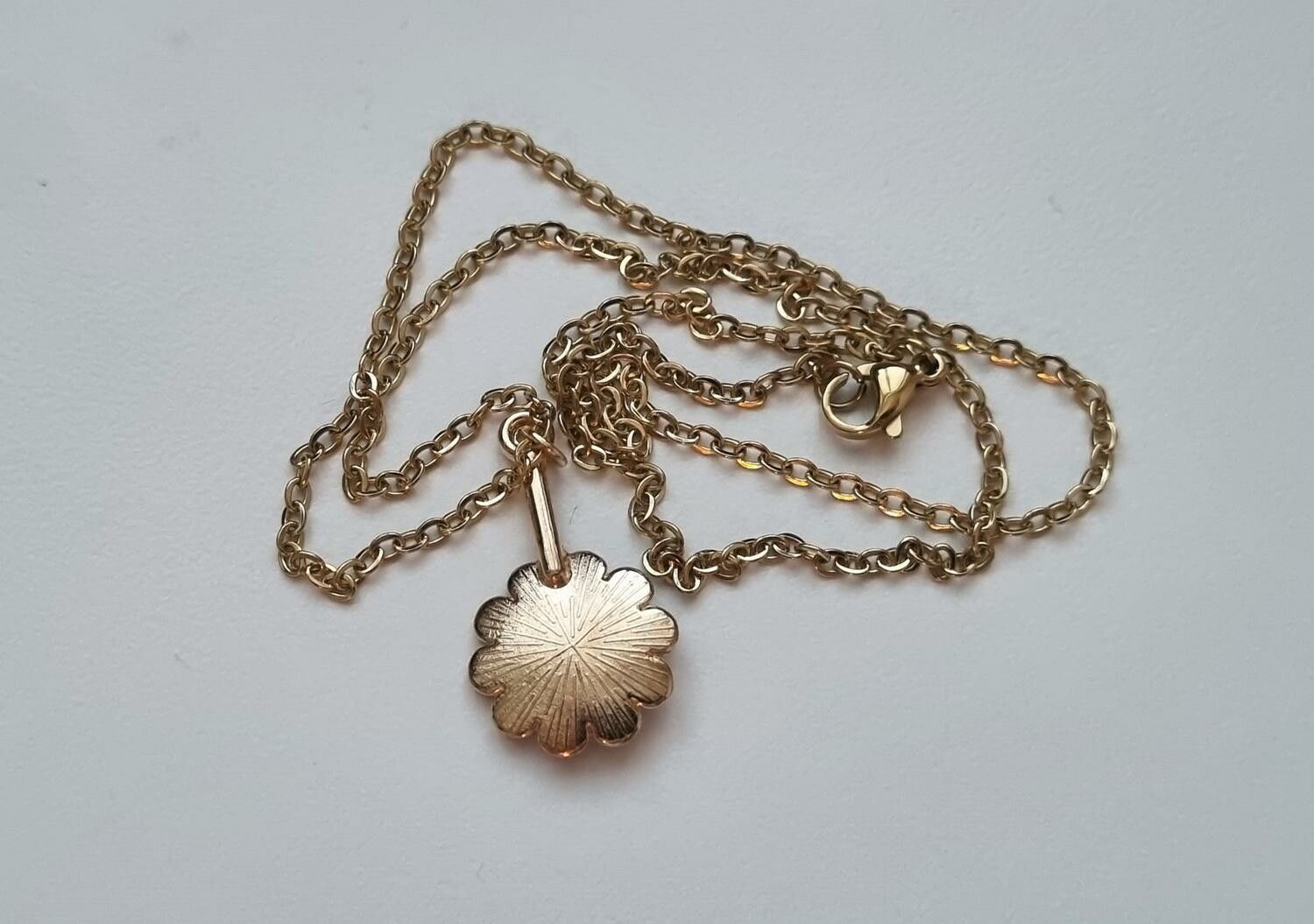 Guldfärgat halsband med en vit blomma, blomberlock / charm