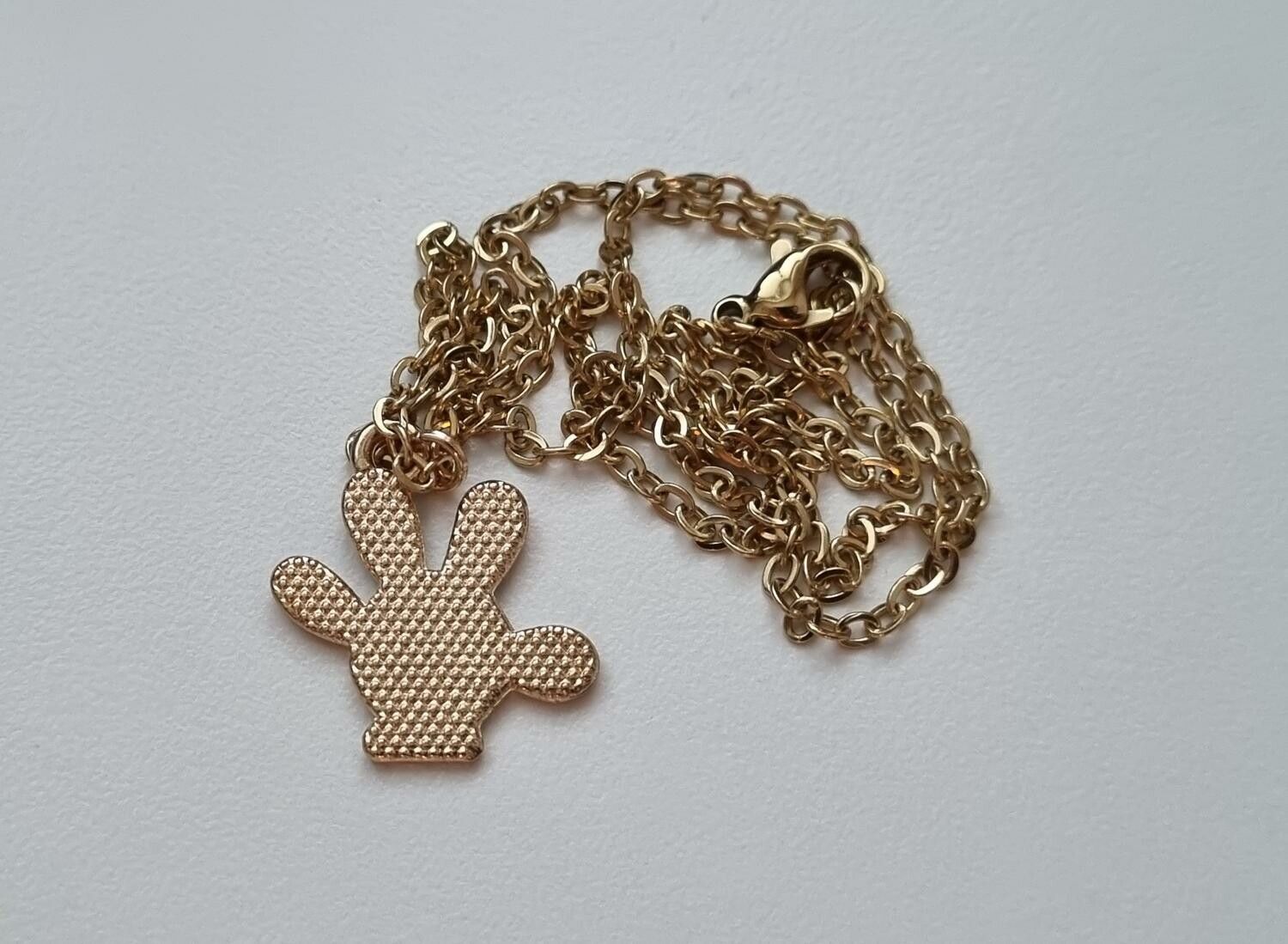 Guldfärgat halsband med en svart hand, berlock / charm