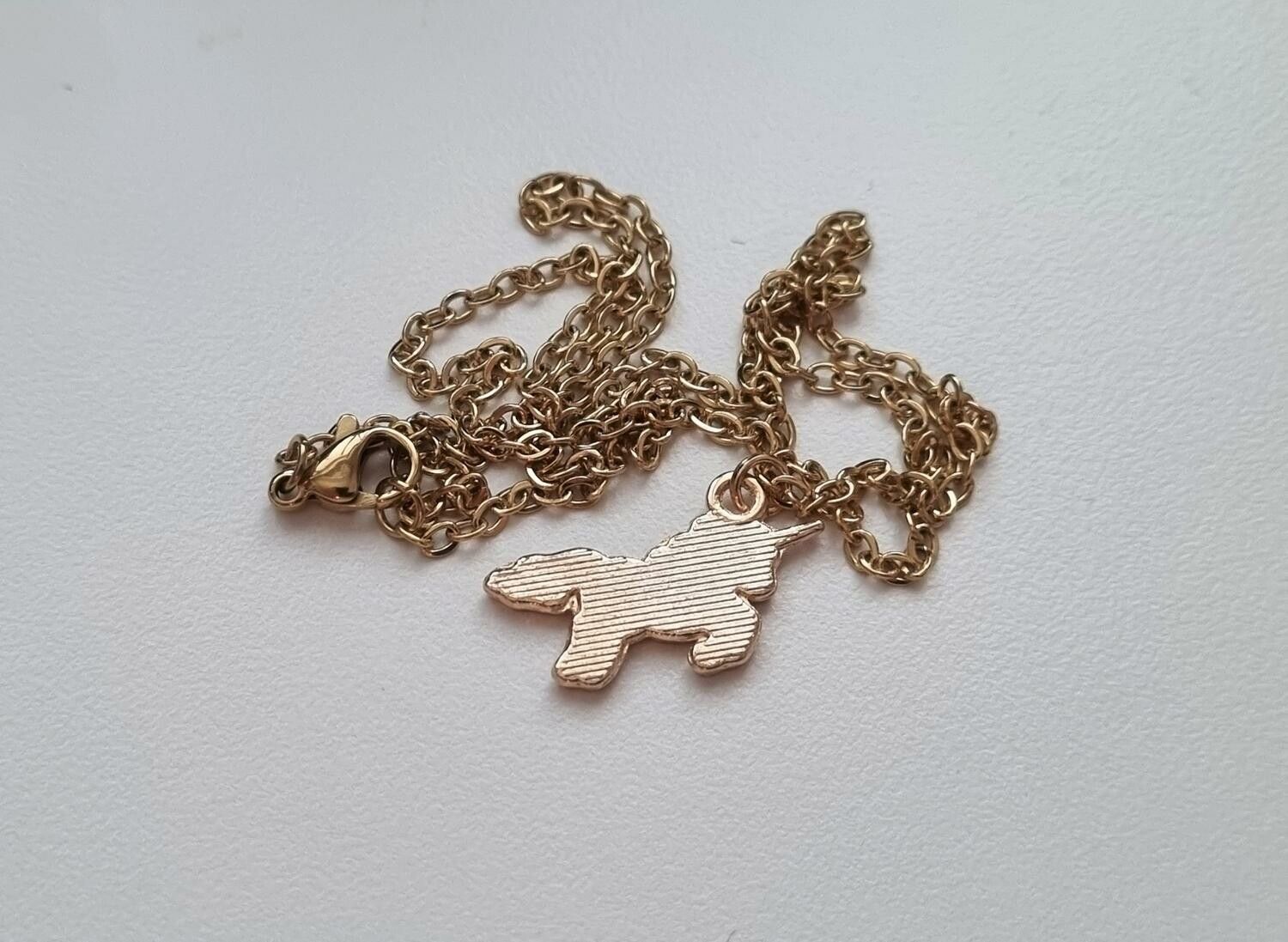 Guldfärgat halsband med en rosa enhörning, berlock / charm