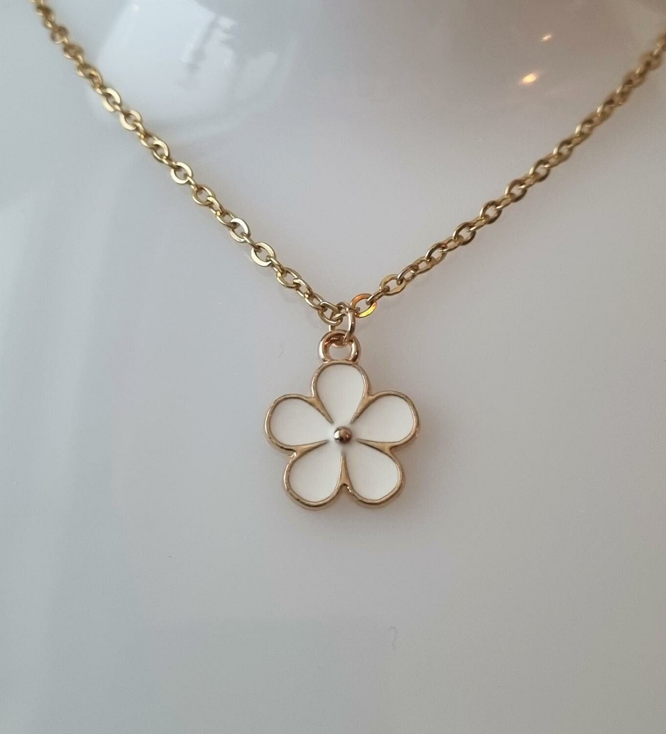 Guldfärgat halsband med en vit blomma, blomberlock / charm
