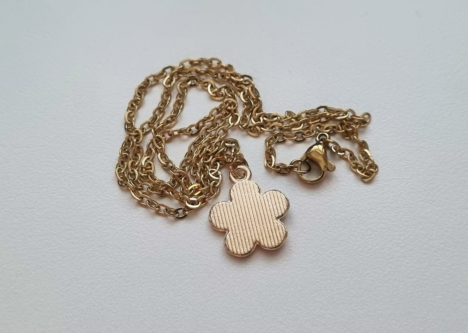 Guldfärgat halsband med en vit blomma, blomberlock / charm