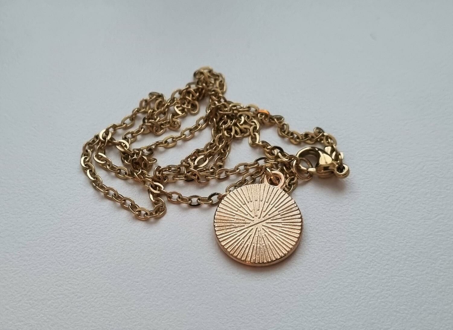 Guldfärgat halsband med en rund berlock / charm