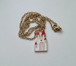Guldfärgat halsband med ett vitt slott. Berlock / charm