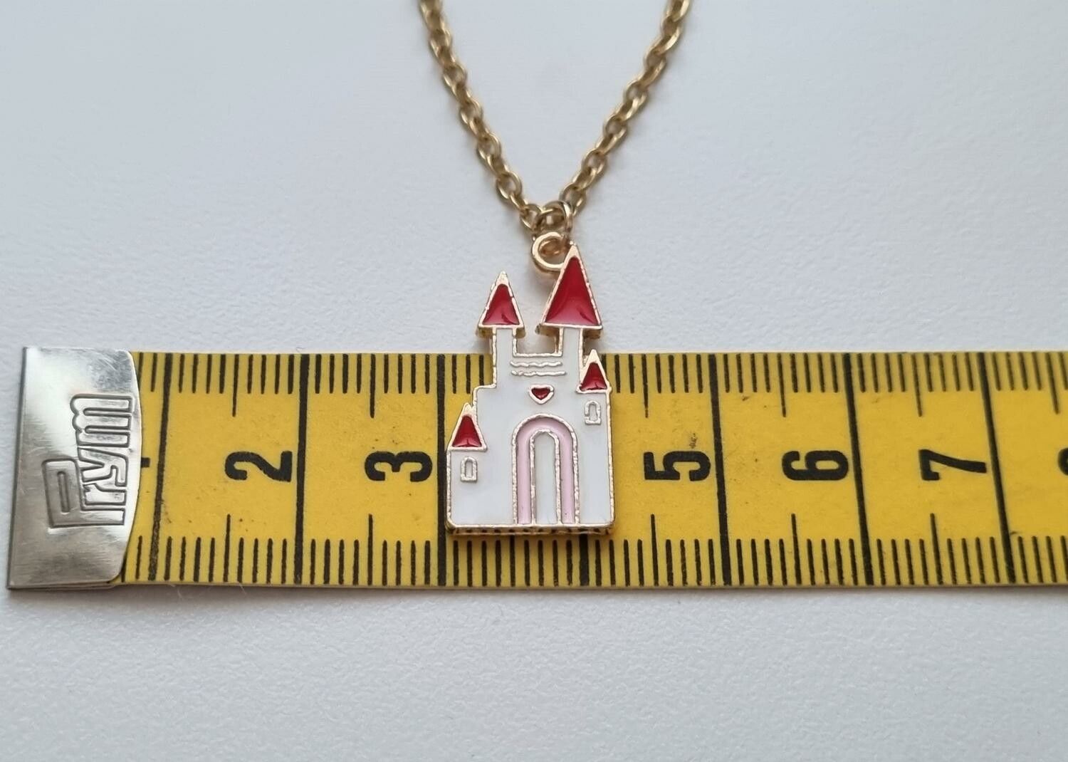 Guldfärgat halsband med ett vitt slott. Berlock / charm