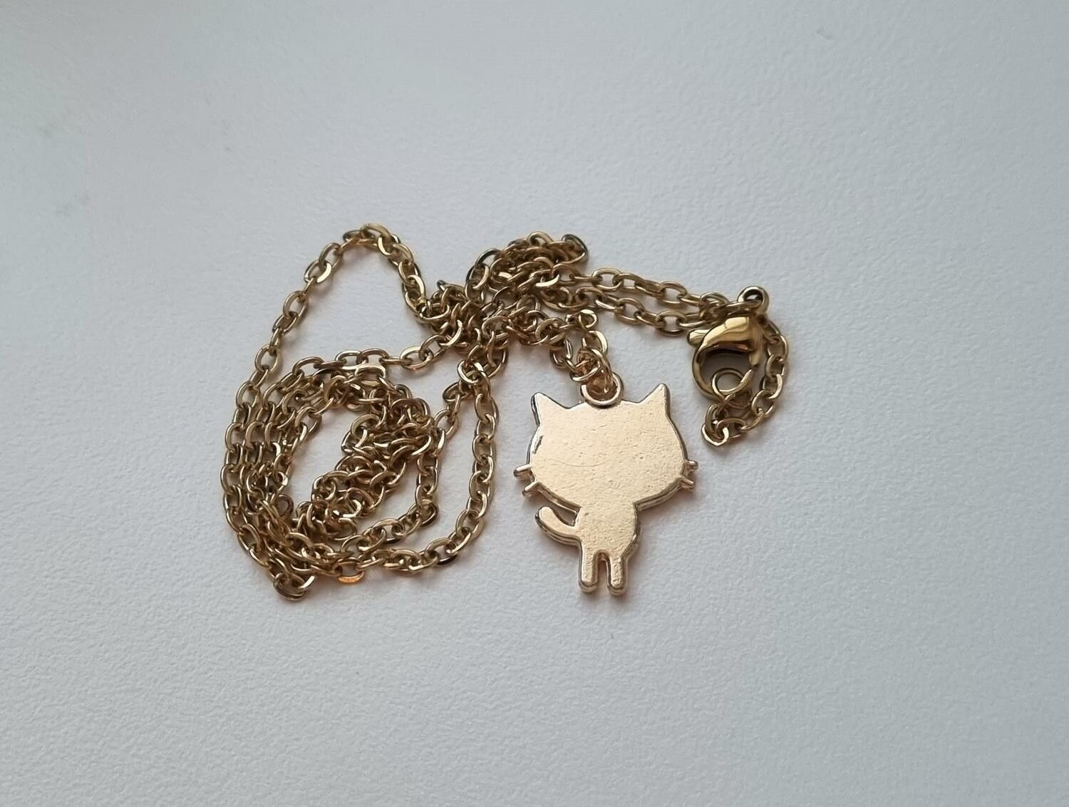 Guldfärgat halsband med en vit katt som berlock / charm