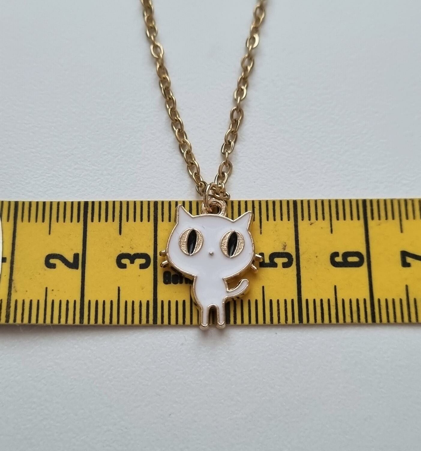 Guldfärgat halsband med en vit katt som berlock / charm