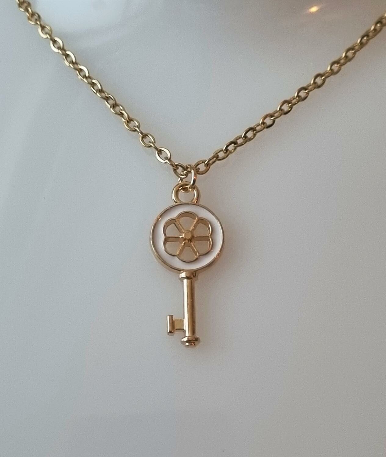 Guldfärgat halsband med en vit nyckel som berlock / charm