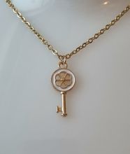 Guldfärgat halsband med en vit nyckel som berlock / charm
