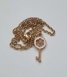 Guldfärgat halsband med en vit nyckel som berlock / charm