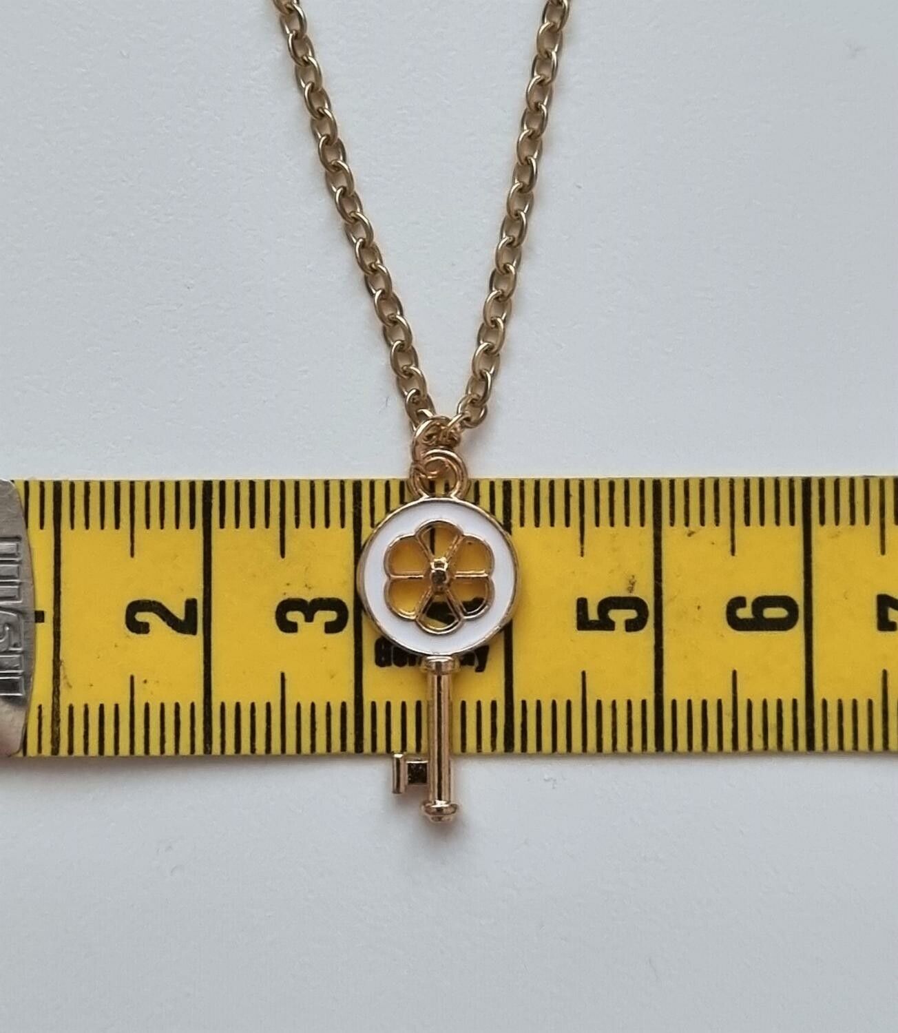 Guldfärgat halsband med en vit nyckel som berlock / charm
