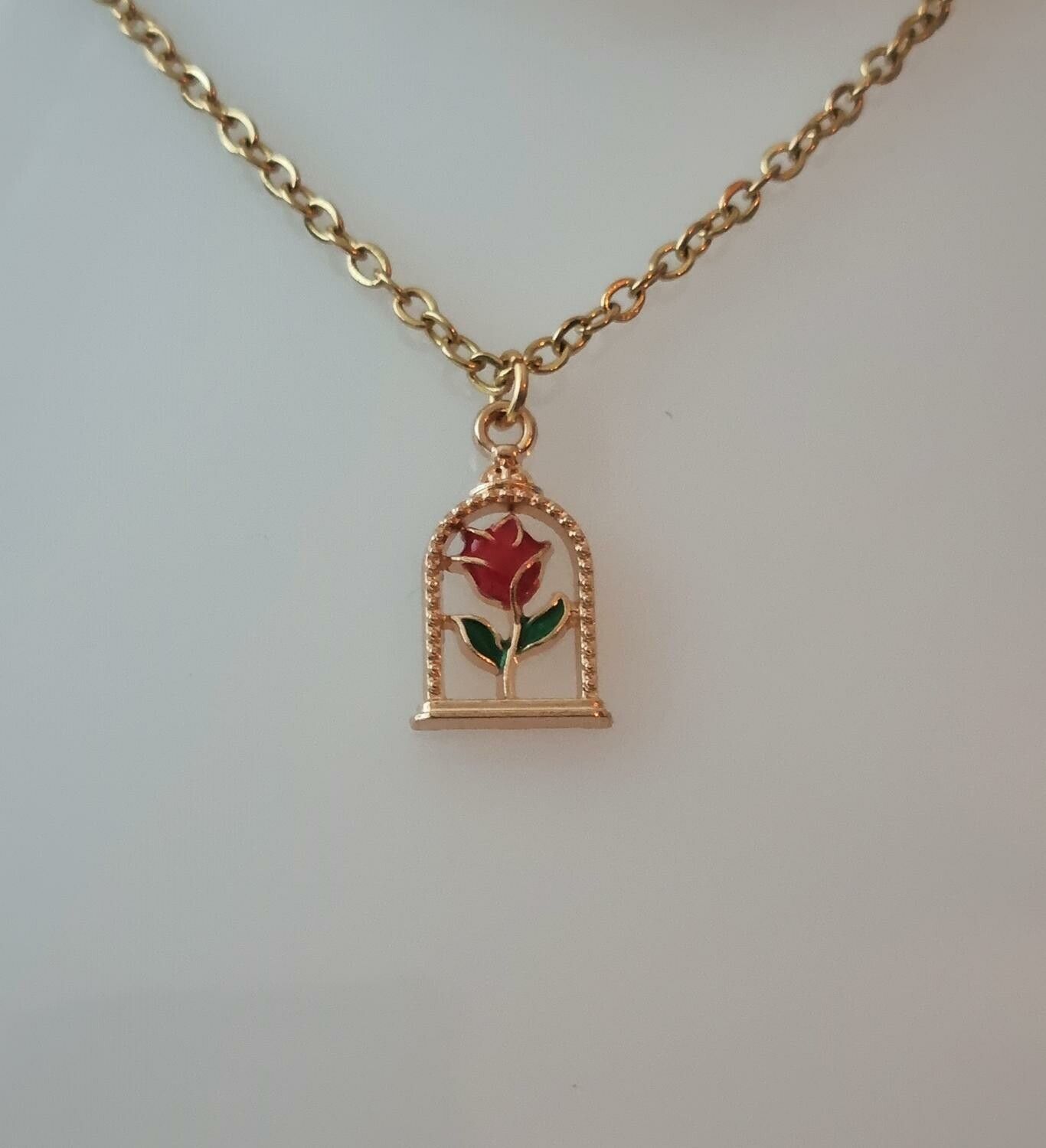 Guldfärgat halsband (50 cm) med en röd ros i en bur