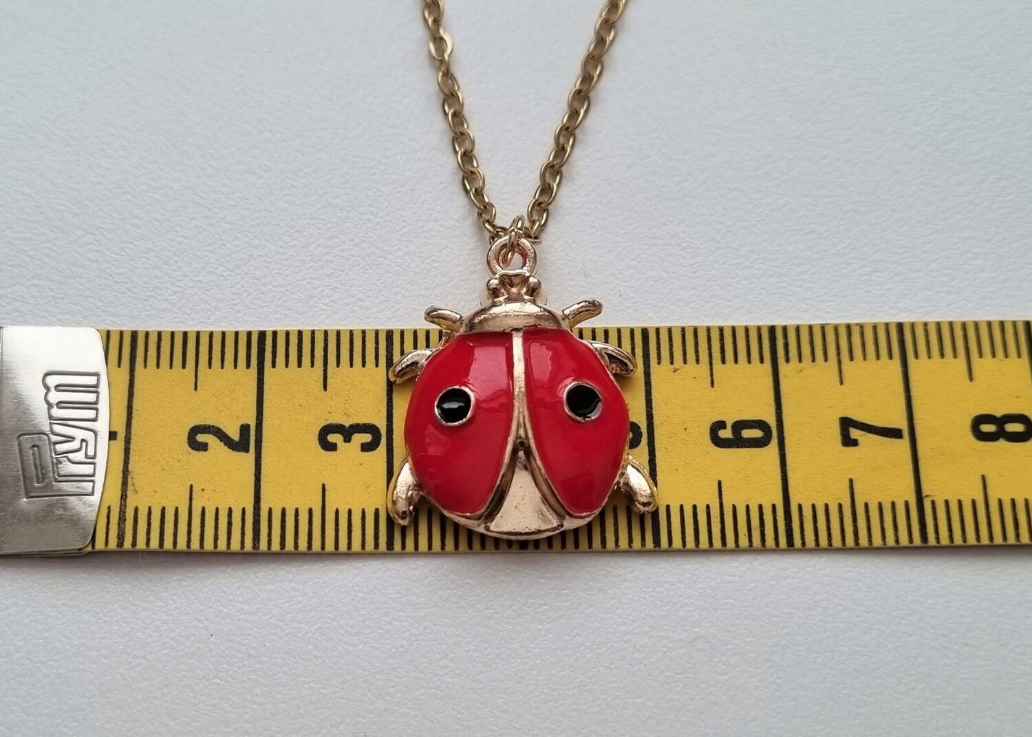 Guldfärgat halsband (50 cm) med en röd skalbagge