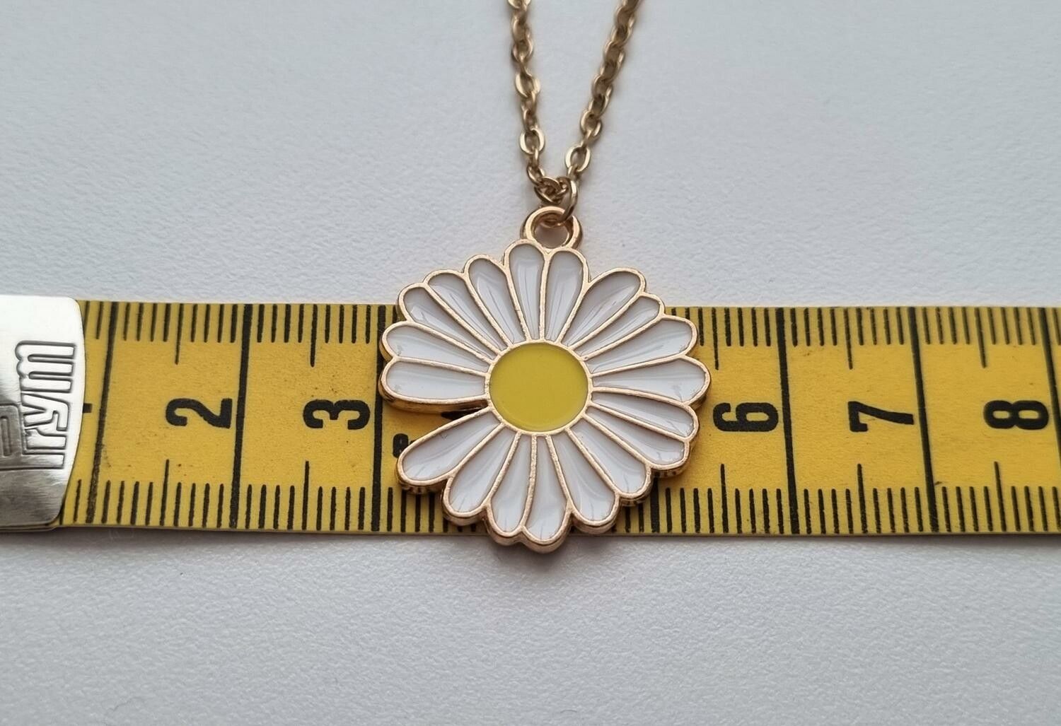 Guldfärgat halsband (50 cm) med en vit blomma