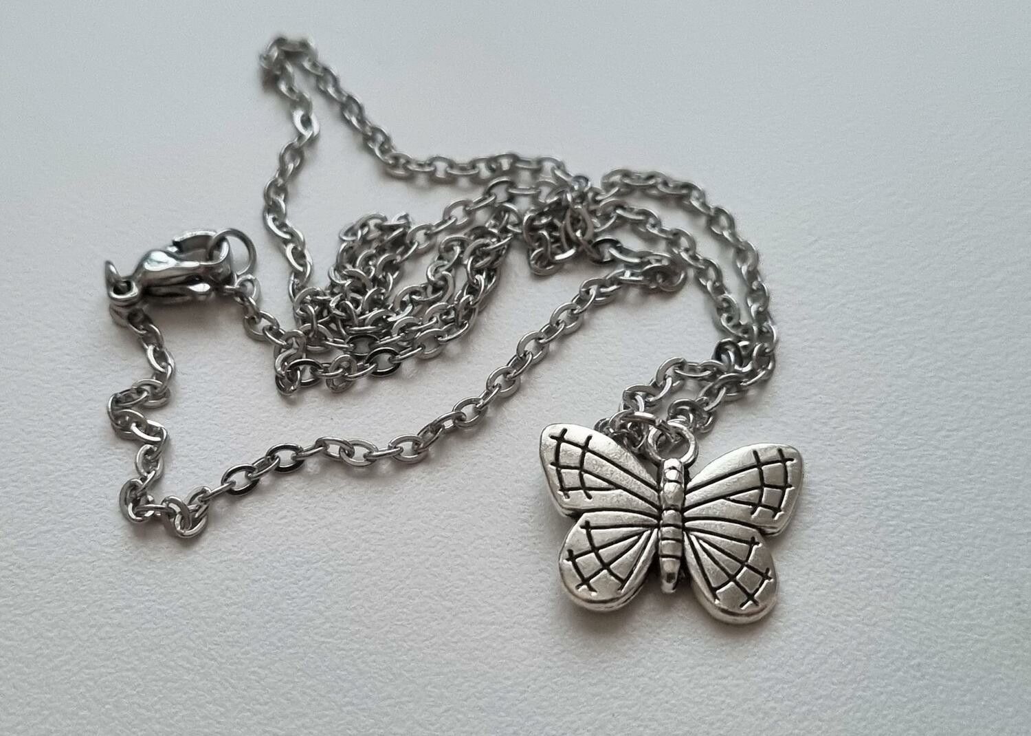 Silverfärgat halsband (45 cm) med en söt fjäril