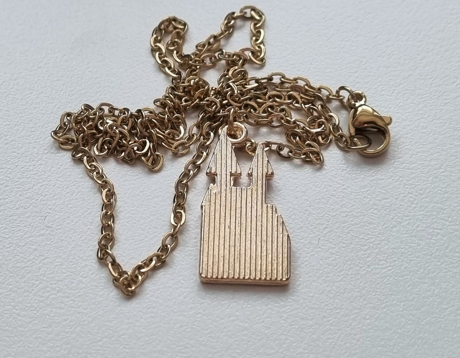 Guldfärgat halsband (50 cm) med ett slott som berlock