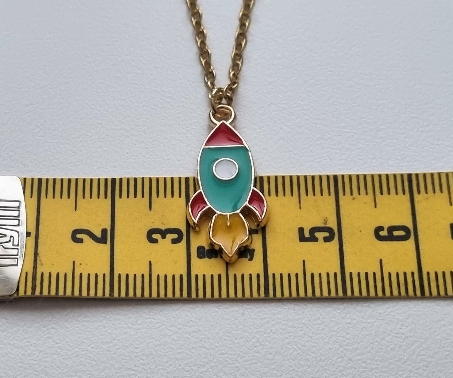 Guldfärgat halsband (50 cm) med en färgglad raket som berlock
