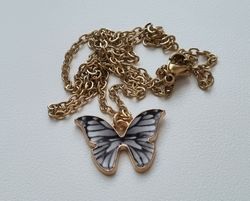 Guldfärgat halsband i rostfritt stål med en gråsvart fjäril