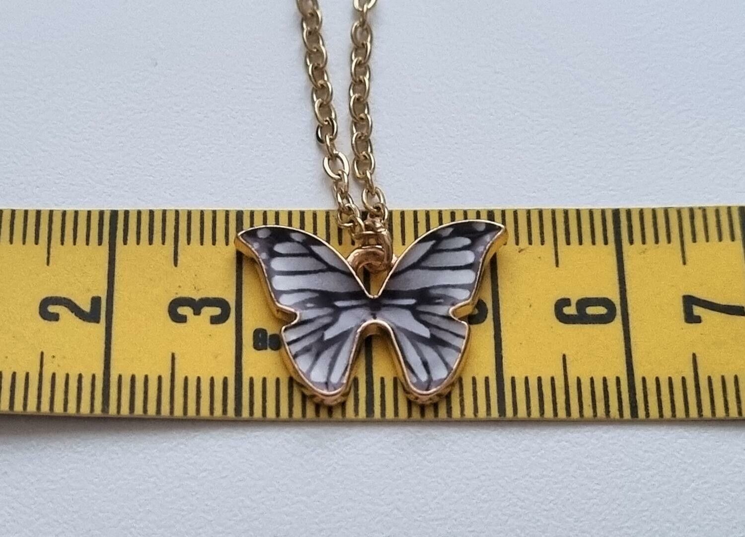 Guldfärgat halsband i rostfritt stål med en gråsvart fjäril