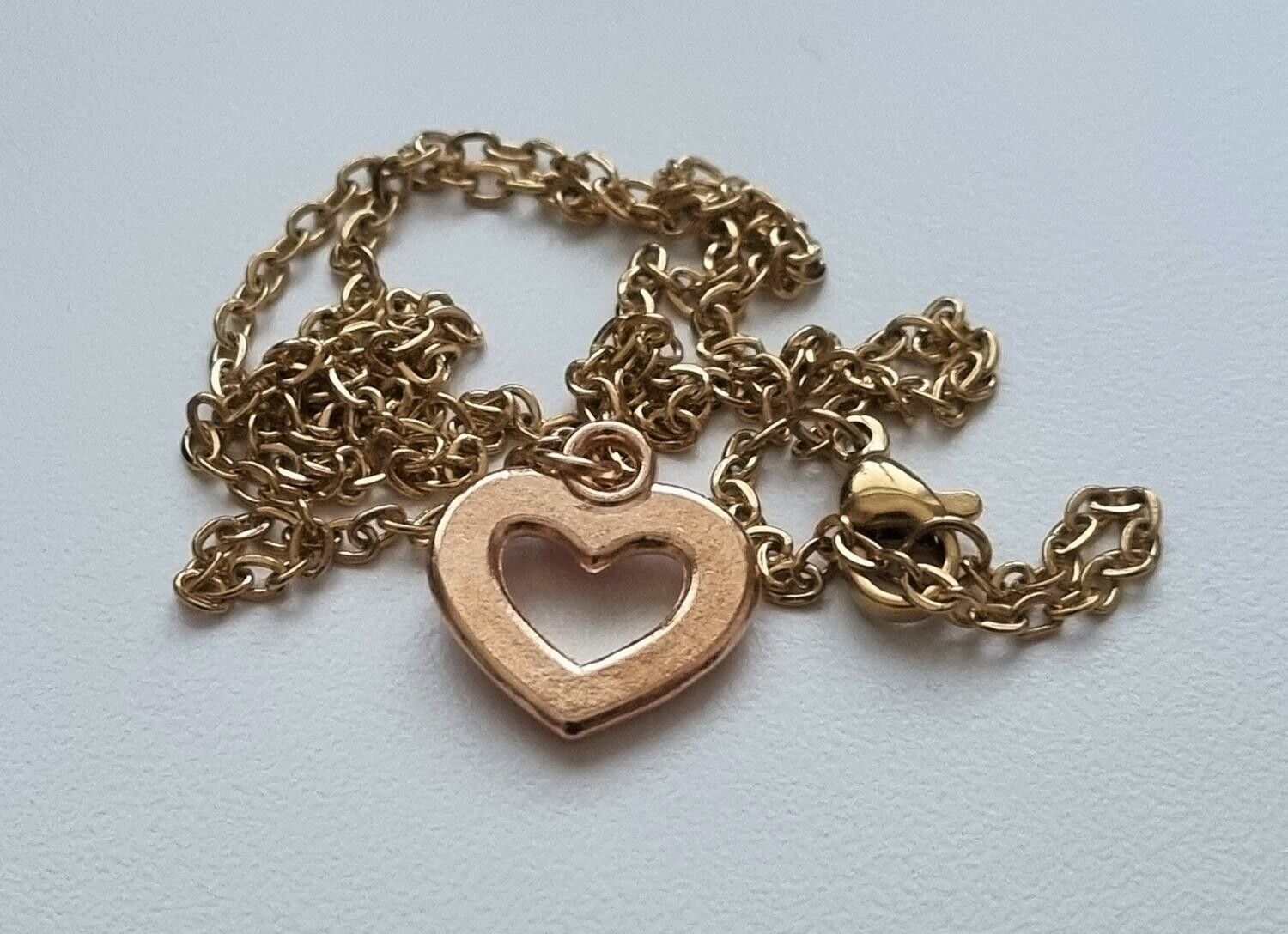 Guldfärgat halsband i rostfritt stål med ett rosa hjärta