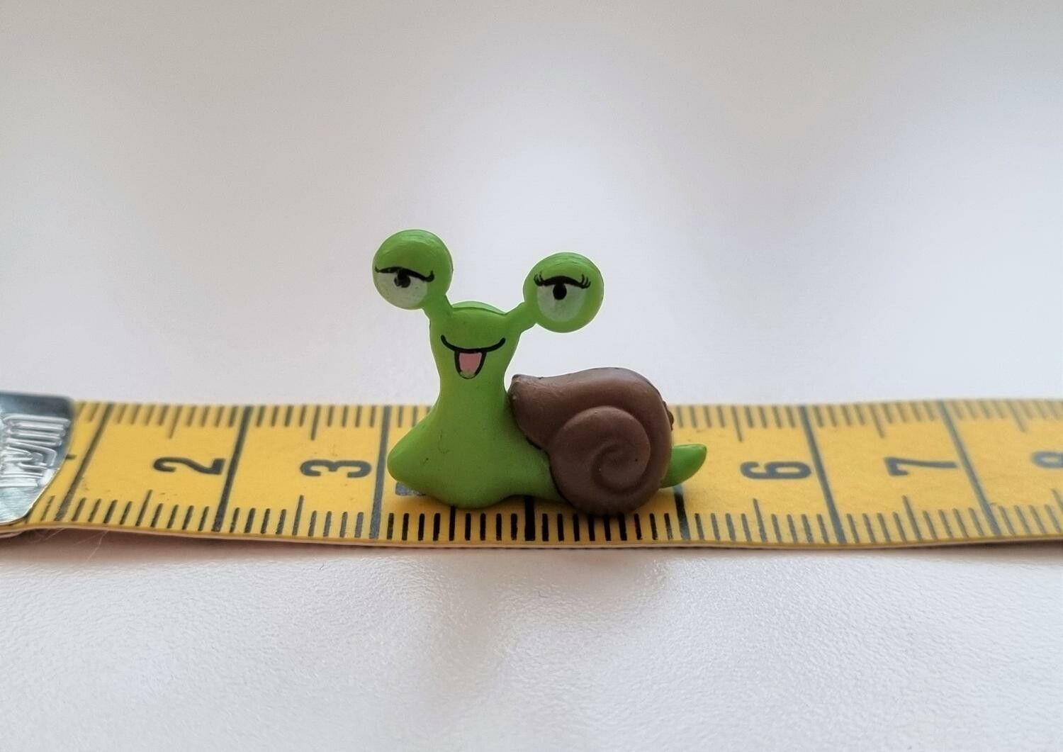 1 st grön snigel med brunt skal. Miniatyr / figurin för dekoration