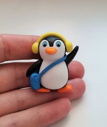 Pingvin med blå väska och gula öronvärmare. Miniatyr / figur för dekoration