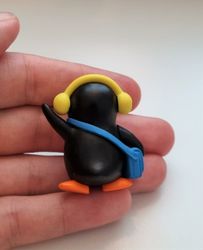 Pingvin med blå väska och gula öronvärmare. Miniatyr / figur för dekoration