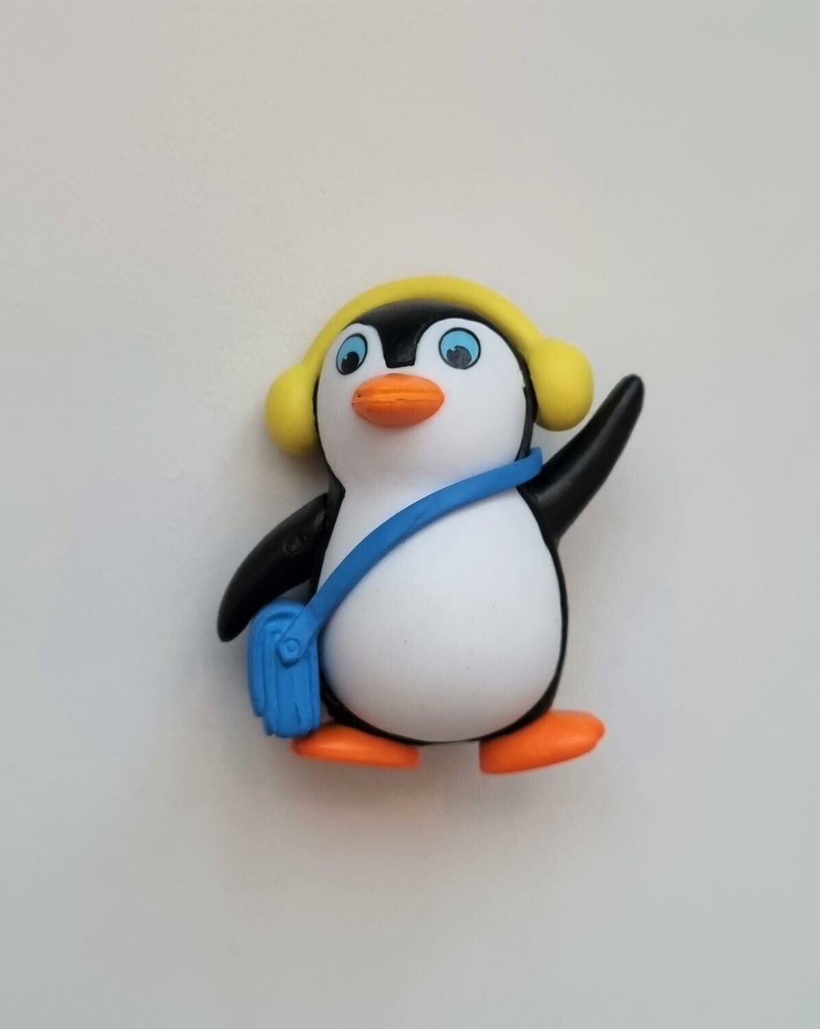 Pingvin med blå väska och gula öronvärmare. Miniatyr / figur för dekoration