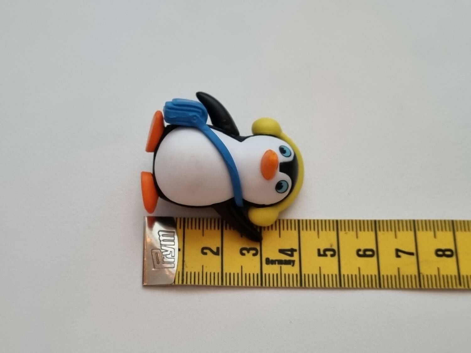 Pingvin med blå väska och gula öronvärmare. Miniatyr / figur för dekoration