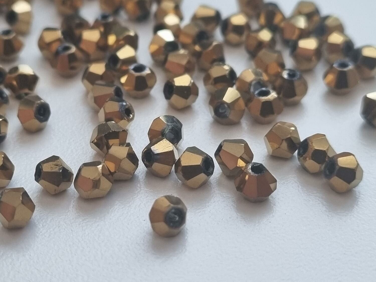 100 st guldfärgade bicone pärlor (4 mm)