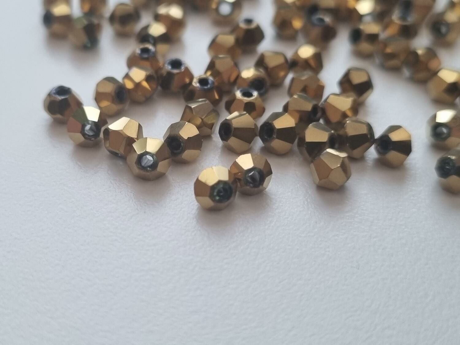 100 st guldfärgade bicone pärlor (4 mm)