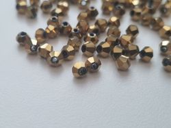 100 st guldfärgade bicone pärlor (4 mm)