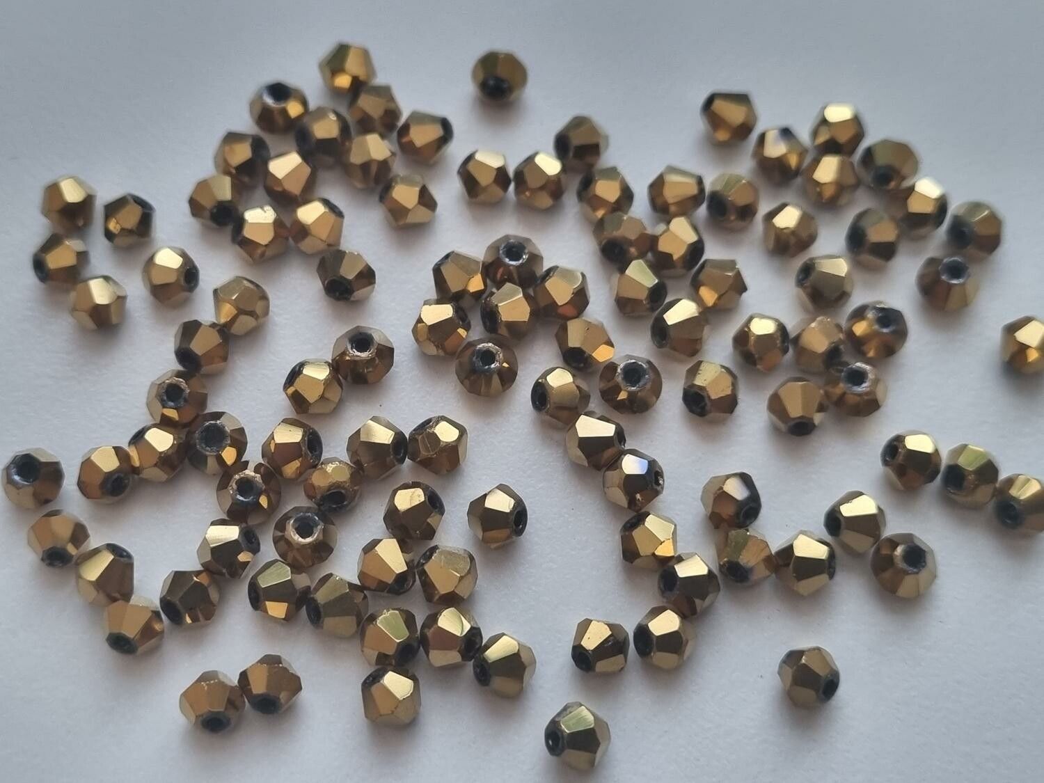 100 st guldfärgade bicone pärlor (4 mm)
