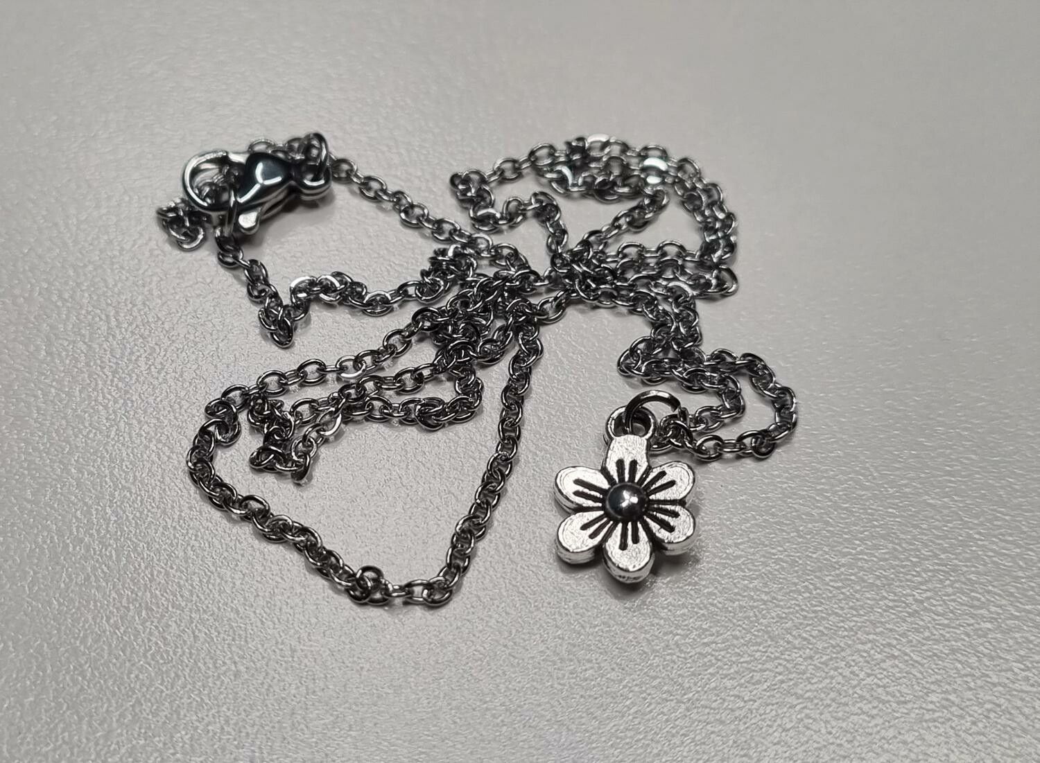 Halsband med en silverfärgad liten blomma / charm