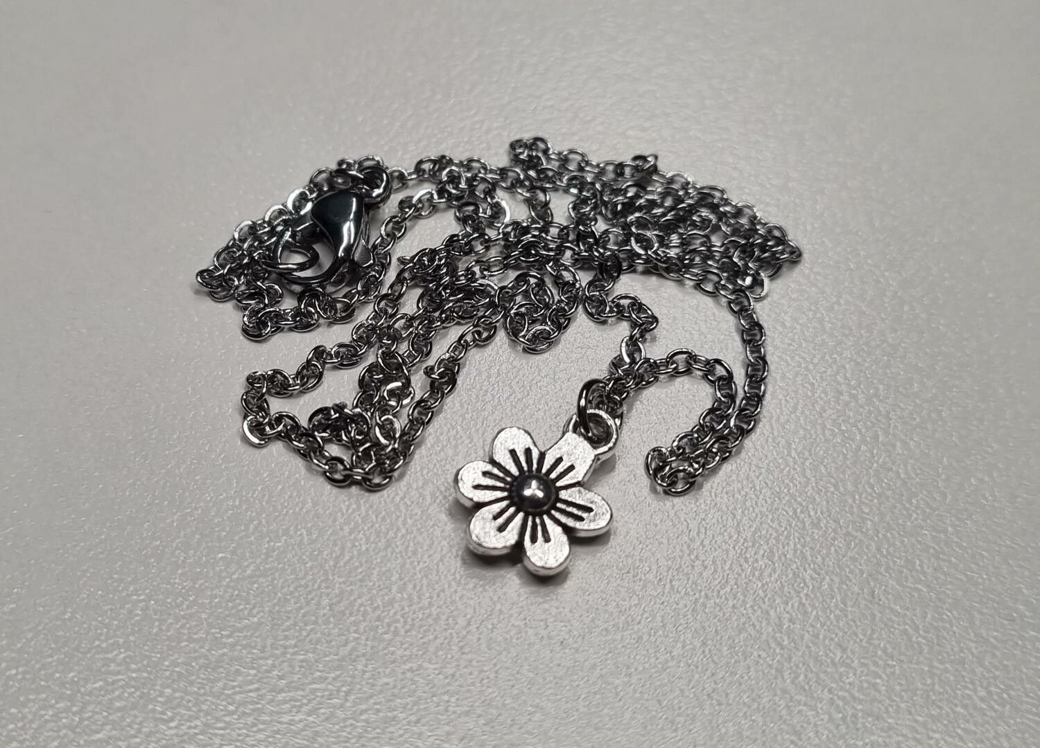 Halsband med en silverfärgad liten blomma / charm