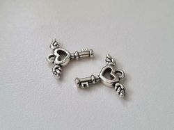 2 st silverfärgade nycklar med vingar. Berlocker / charms