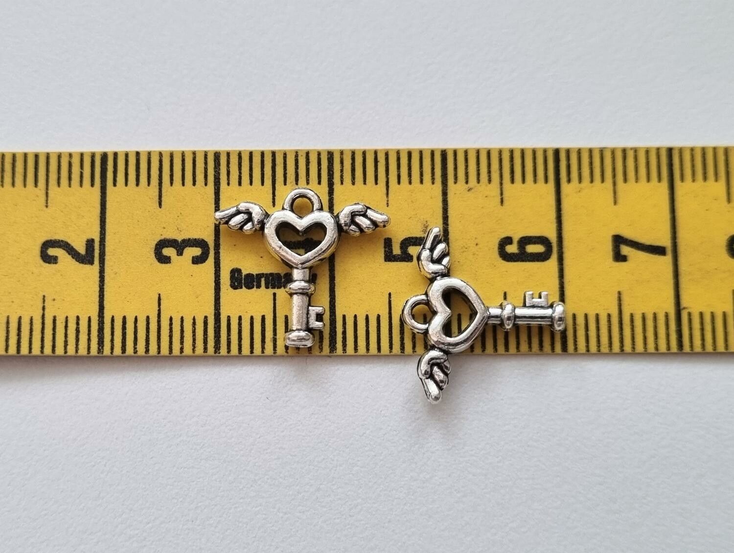 2 st silverfärgade nycklar med vingar. Berlocker / charms