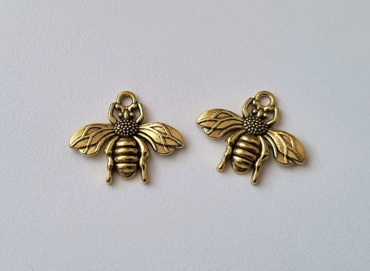2 st guldfärgade bin,. Berlocker / charms