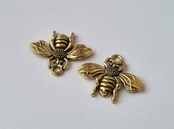 2 st guldfärgade bin,. Berlocker / charms