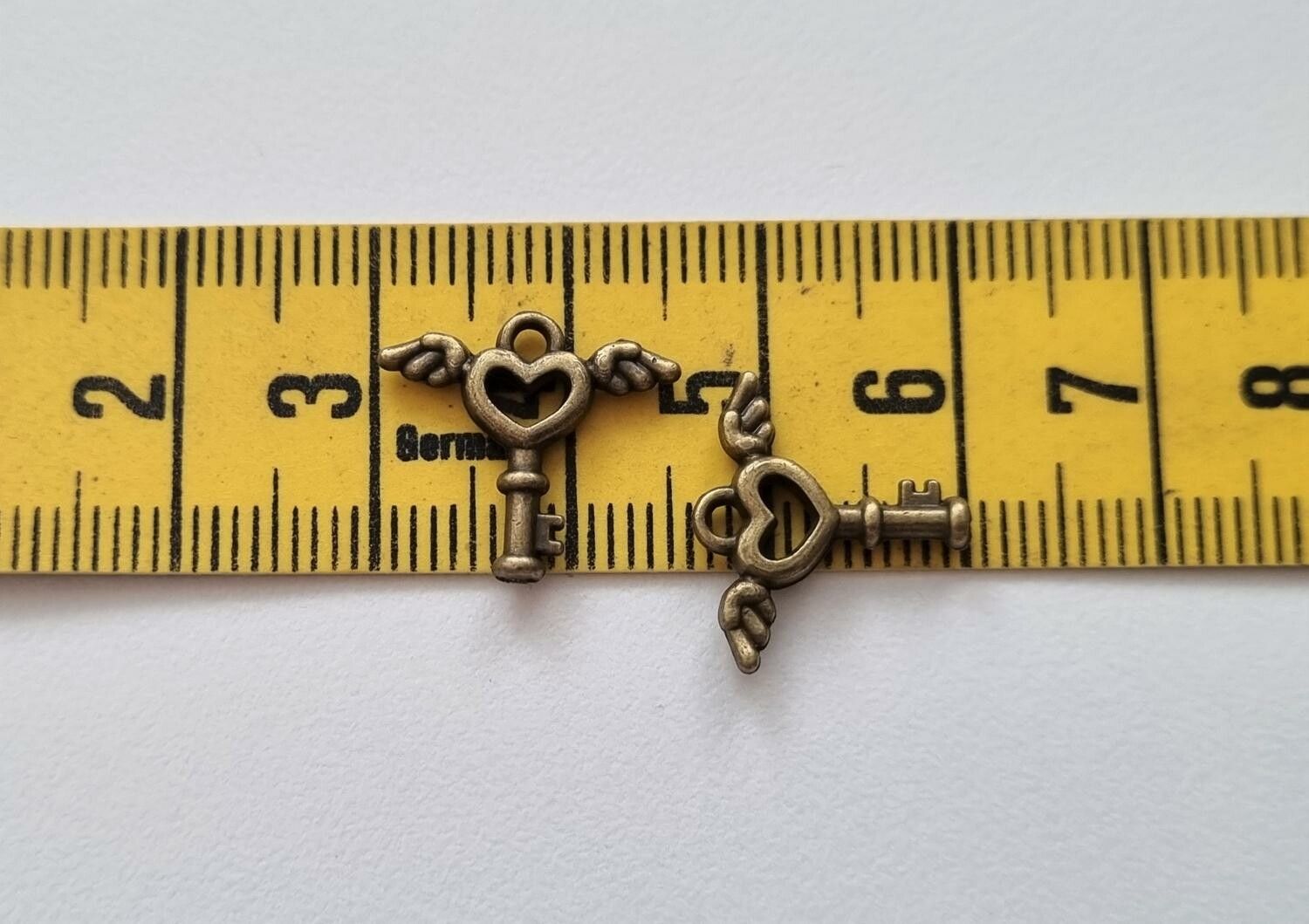 2 st bronsfärgade nycklar med vingar. Berlocker / charms