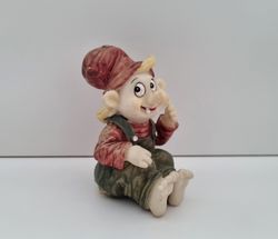 Tomtenisse som sitter på rumpan