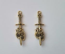 2 st guldfärgade dödskallesvärd genom ett hjärta,. Berlocker / charms