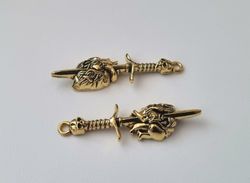 2 st guldfärgade dödskallesvärd genom ett hjärta,. Berlocker / charms