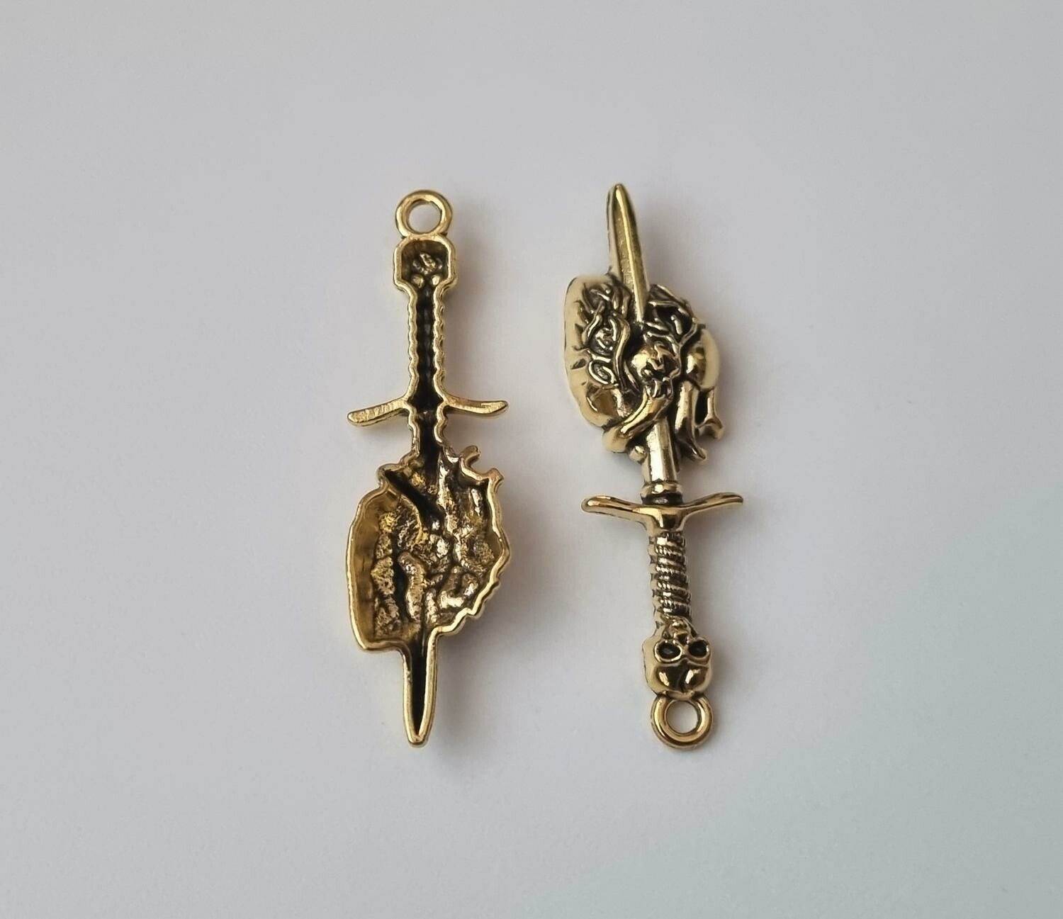 2 st guldfärgade dödskallesvärd genom ett hjärta,. Berlocker / charms