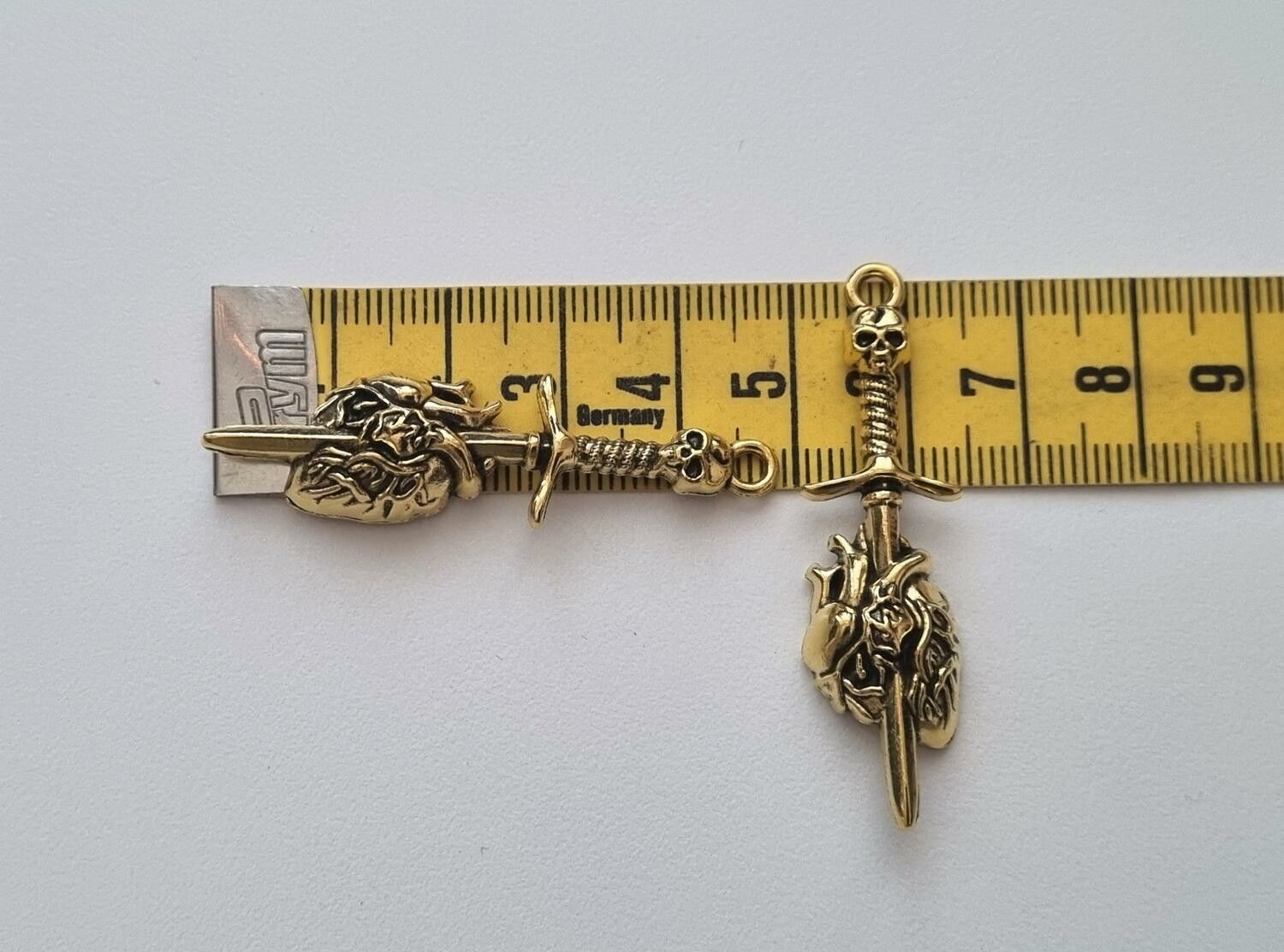 2 st guldfärgade dödskallesvärd genom ett hjärta,. Berlocker / charms