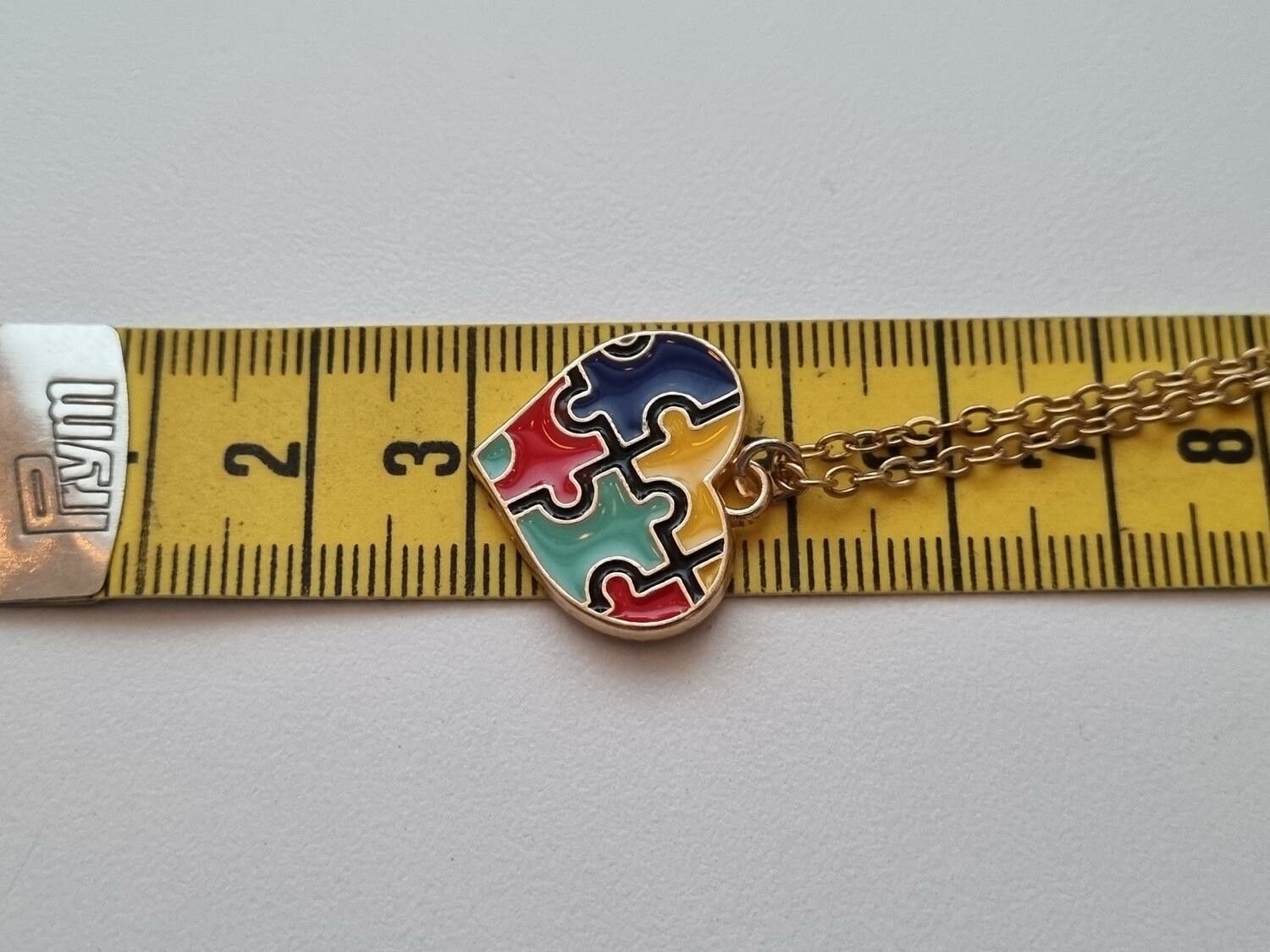 Guldfärgat halsband med flerfärgad pusselbit / medvetenhet