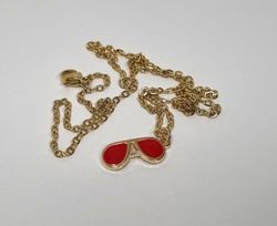 Guldfärgat halsband med ett par röda glasögon