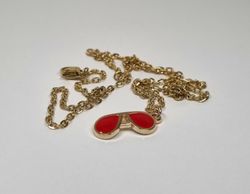 Guldfärgat halsband med ett par röda glasögon
