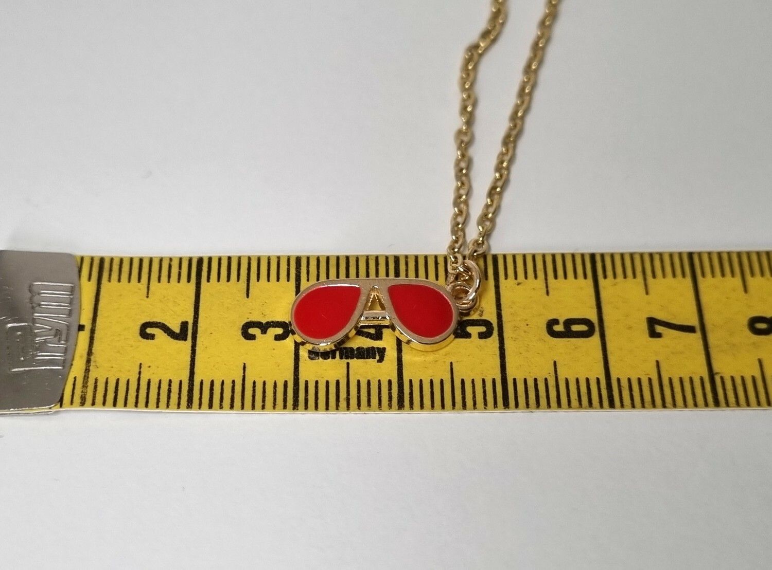 Guldfärgat halsband med ett par röda glasögon